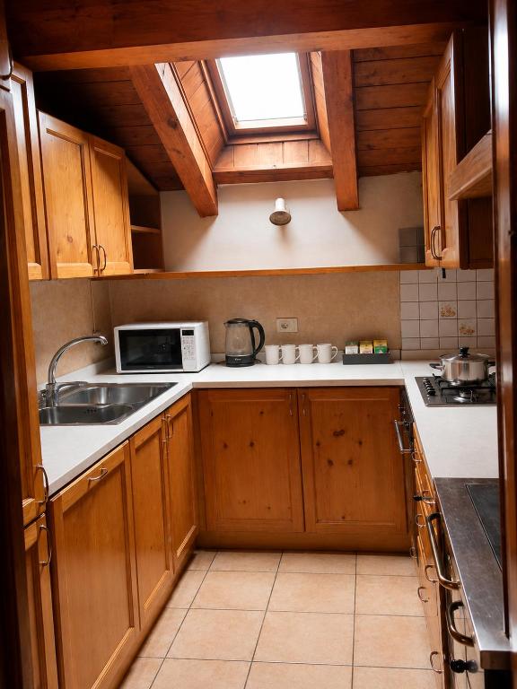 Cucina attrezzata in legno con lavastoviglie, forno, piano cottura e microonde